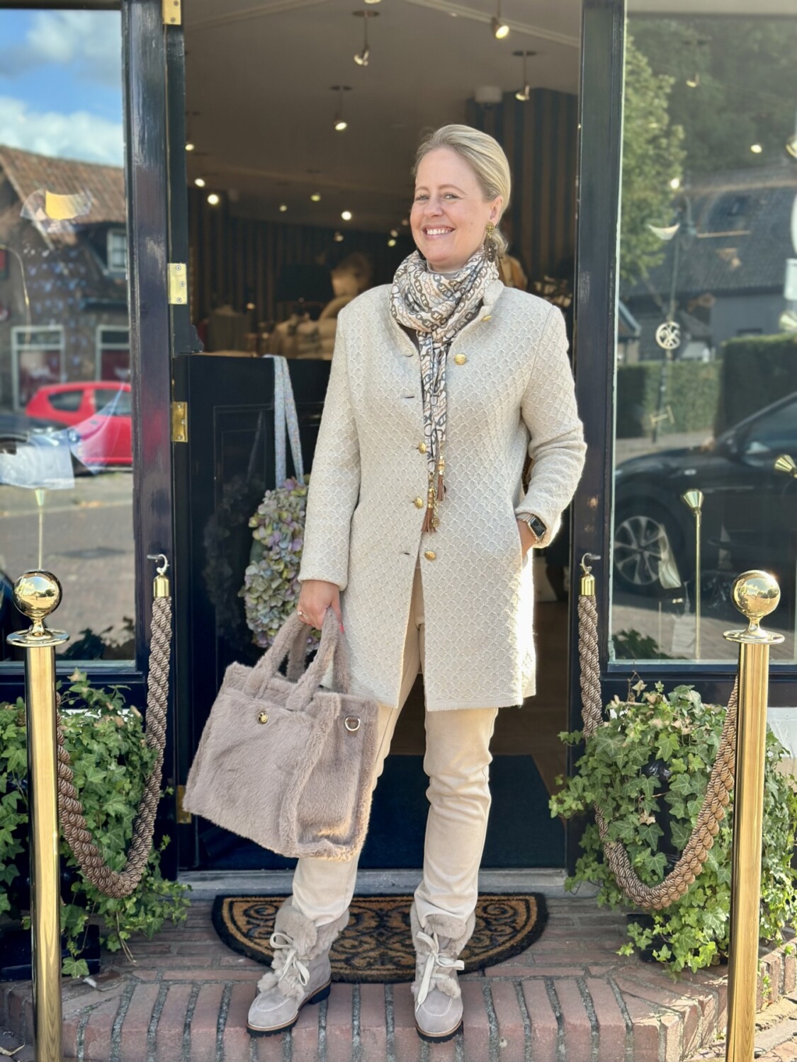 Modici stijlvolle vrouw in beige outfit met luxe jas en tas voor een fashionably elegante look.