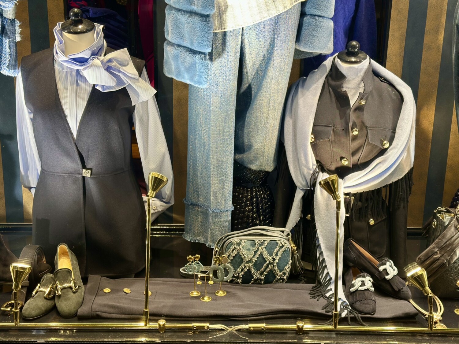 Modici luxe dameskleding en accessoires in een etalage. Elegante outfits, sieradencollectie en stijlvolle schoenen voor moderne vrouwen.