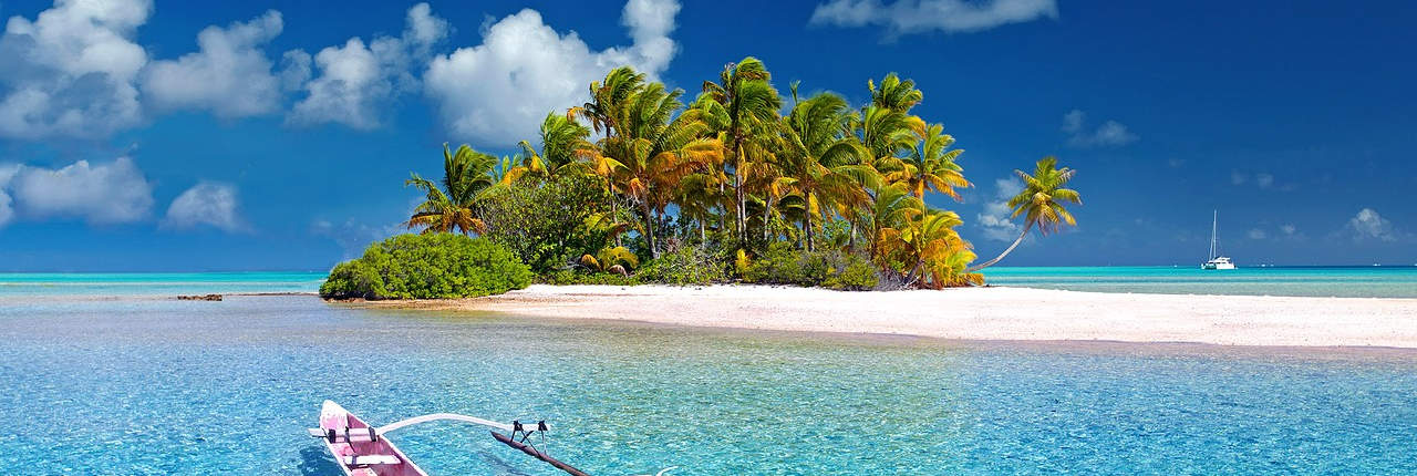 A wide, scenic image of a tropical beach with clear turquoise waters, a boat, and lush palm trees, evoking a sense of vacation, relaxation, or travel.