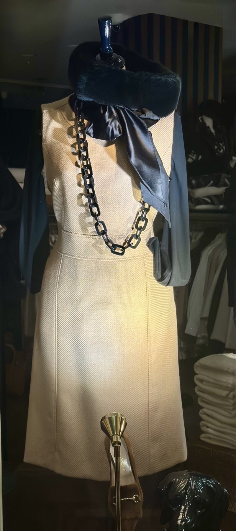 Chique beige jurk met zwart accessoires en statement ketting, stijlvol voor modieuze outfits.