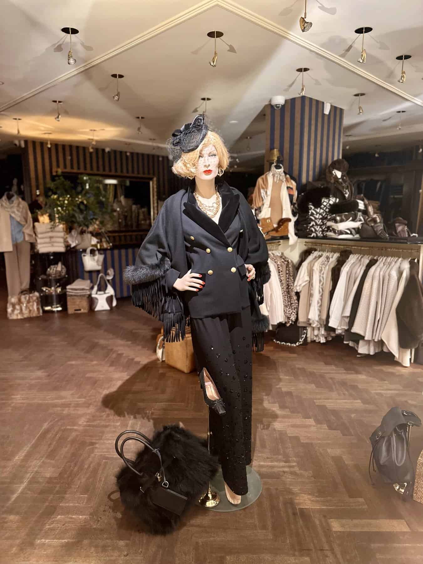 Elegant vrouwelijke mannequin in modieuze zwarte outfit met glamour details in boetiek.